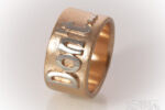 Breiter Ring in Roségold mit einem aufgesetzten Schriftzug in Silber. Text: Don't..