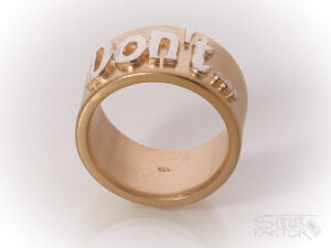 Breiter Ring in Roségold mit einem aufgesetzten Schriftzug in Silber. Text: Don't..